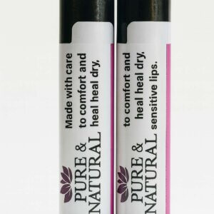 Two Pure & Natural Body Essentials lip balm tubes standing on a wooden table in warm natural light, showcasing their minimalist labels that read “Made with care to comfort and heal dry, sensitive lips.”