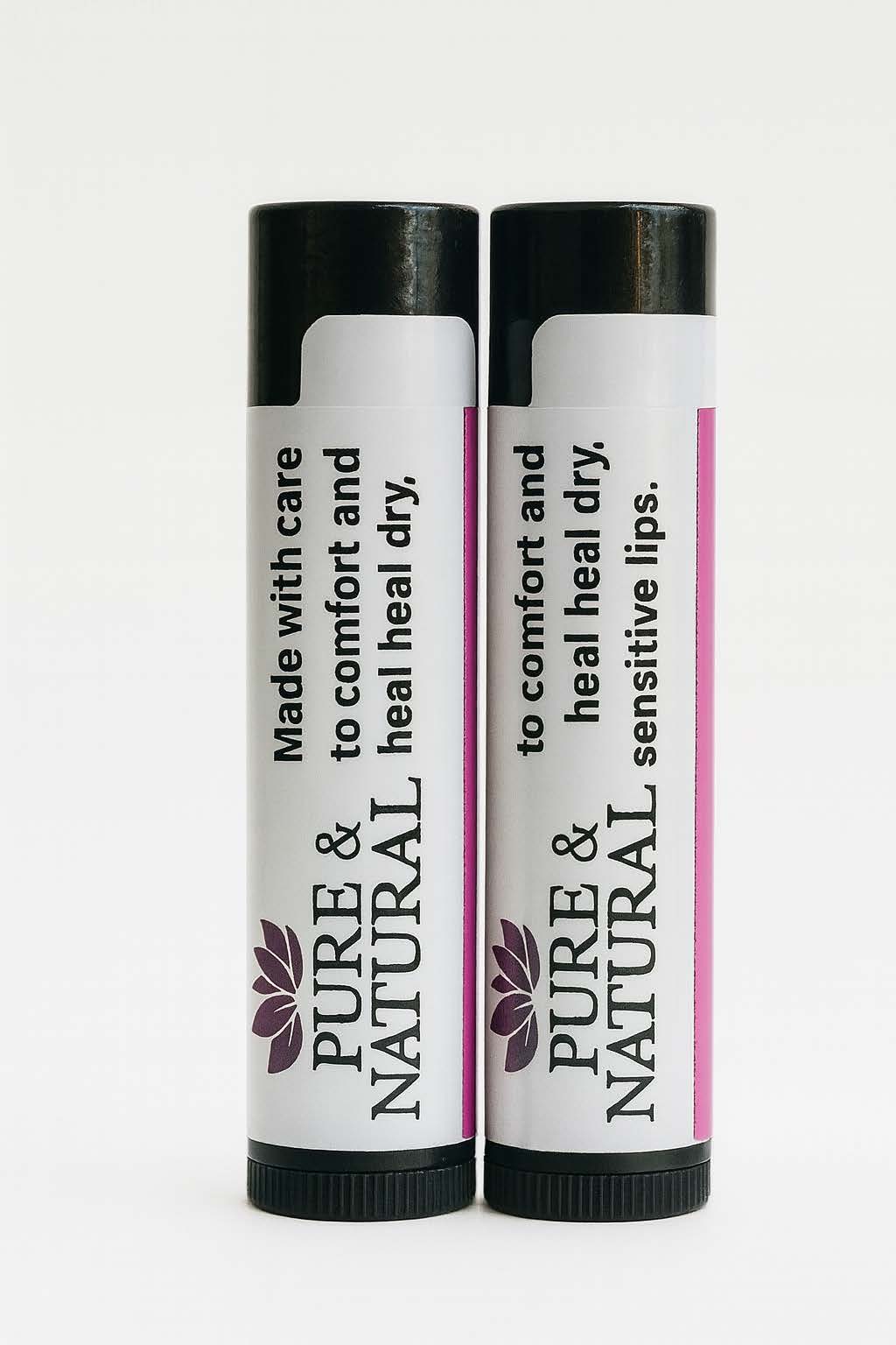 Two Pure & Natural Body Essentials lip balm tubes standing on a wooden table in warm natural light, showcasing their minimalist labels that read “Made with care to comfort and heal dry, sensitive lips.”